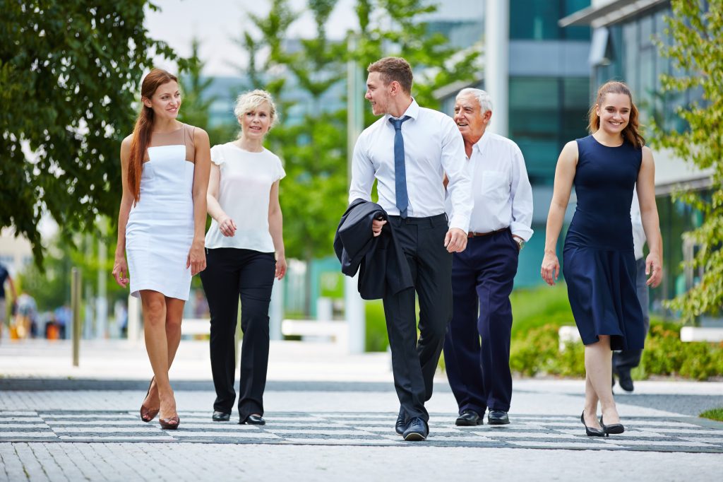 Group of business people walking and talking together outdoors in summer